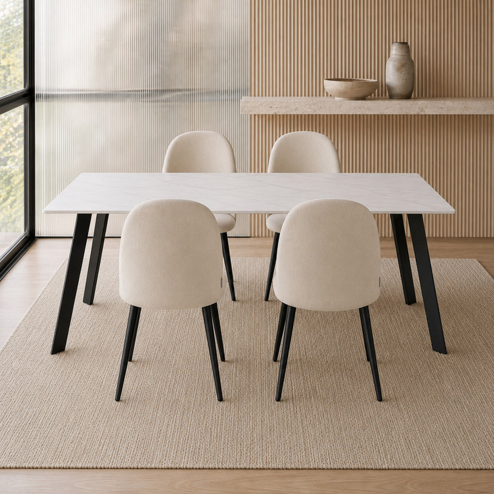 Cuatro sillas Livia Lisa beige ubicadas alrededor de una mesa rectangular blanca con patas negras.