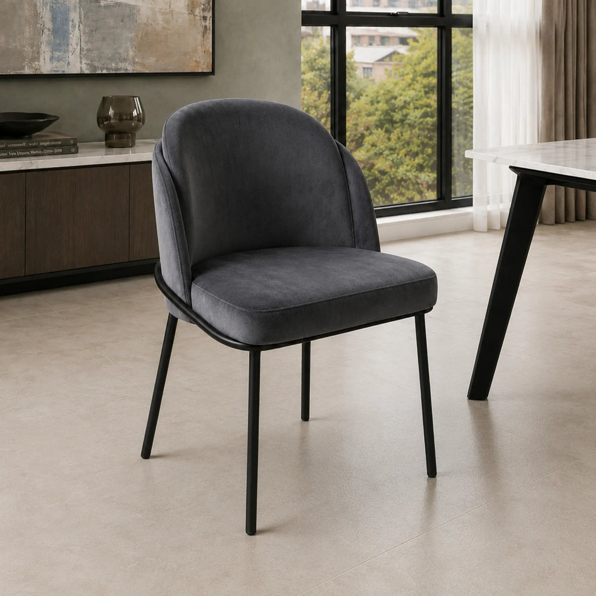 Silla Katia gris oscuro con tapizado de tela y patas negras en un ambiente de living moderno.