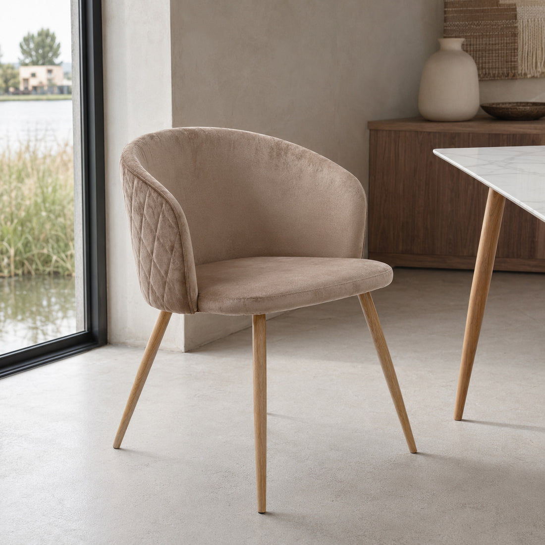 Silla Jade en pana color taupe con base de madera natural y diseño envolvente de líneas curvas.