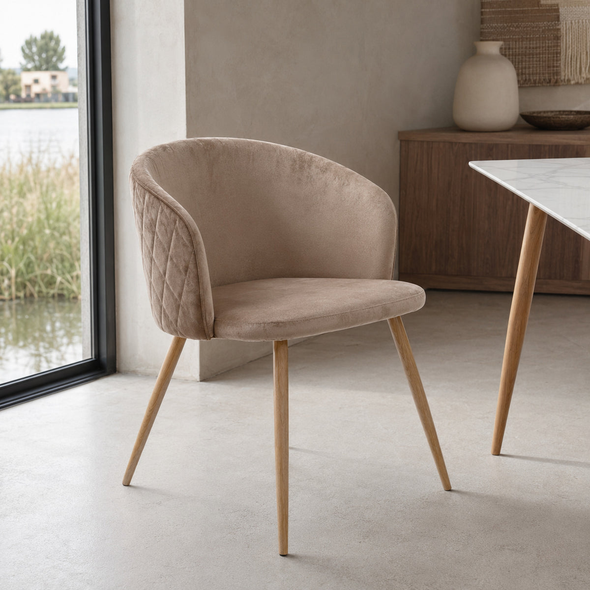 Silla Jade en pana color taupe con base de madera natural y diseño envolvente de líneas curvas.