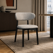 Silla Zuno Deluxe tapizada en chenille gris claro con estructura de madera negra en un ambiente de comedor.