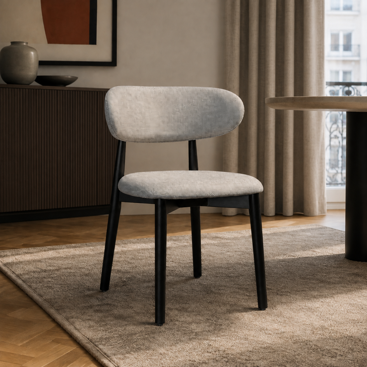 Silla Zuno Deluxe tapizada en chenille gris claro con estructura de madera negra en un ambiente de comedor.