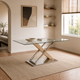 Mesa Calgary con tapa de vidrio rectangular y base en X de madera clara y metal cromado sobre alfombra beige.