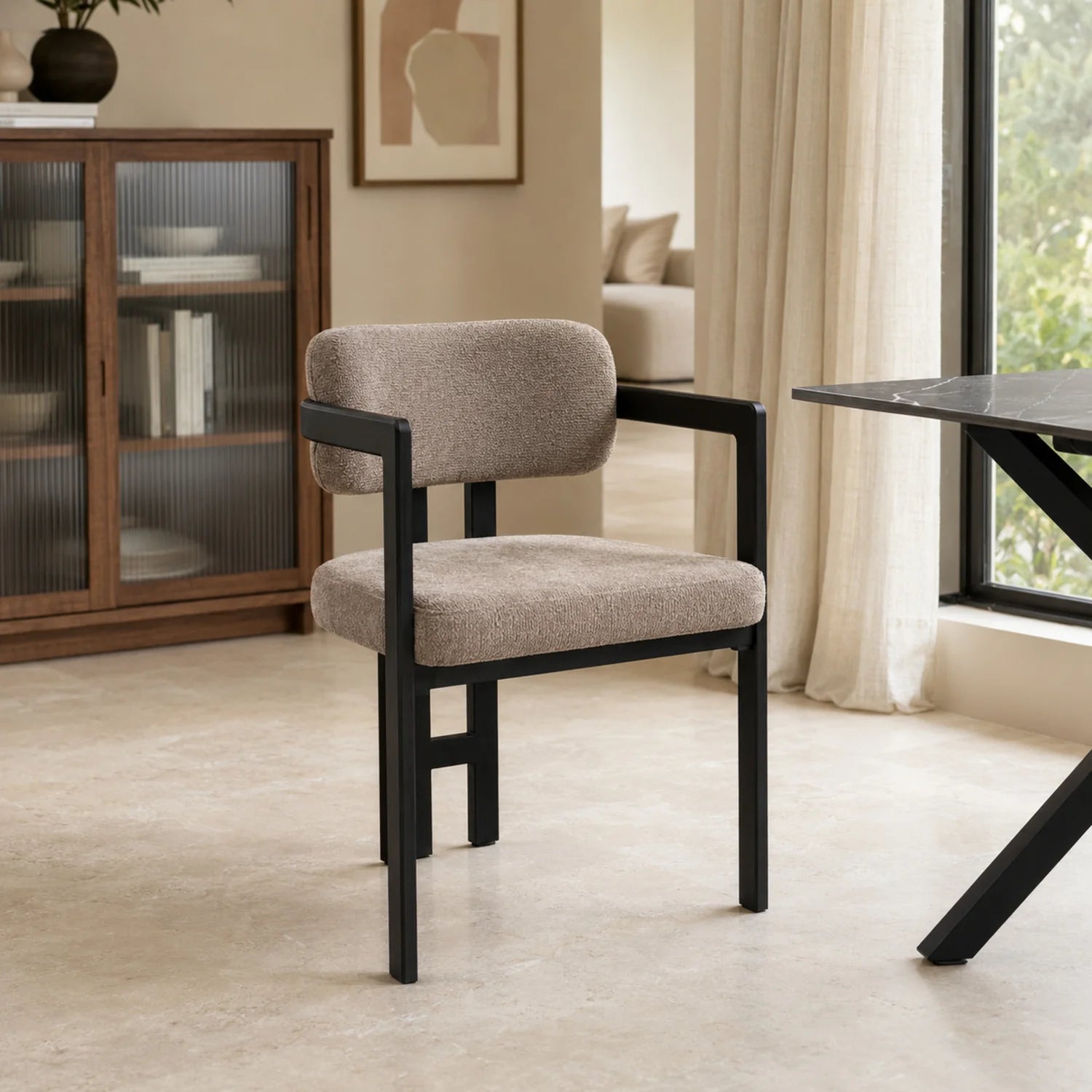 Silla Besaya tapizada en chenille taupe con estructura metálica negra en un living contemporáneo.
