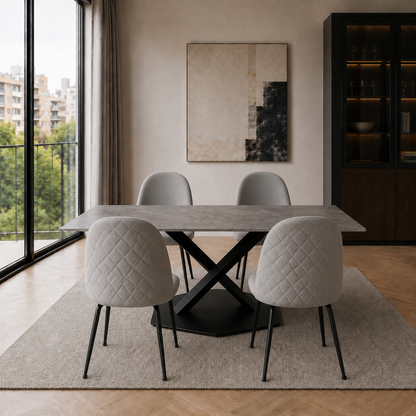Mesa de comedor Cross de mármol gris y base negra ambientada con cuatro sillas tapizadas en tono claro.