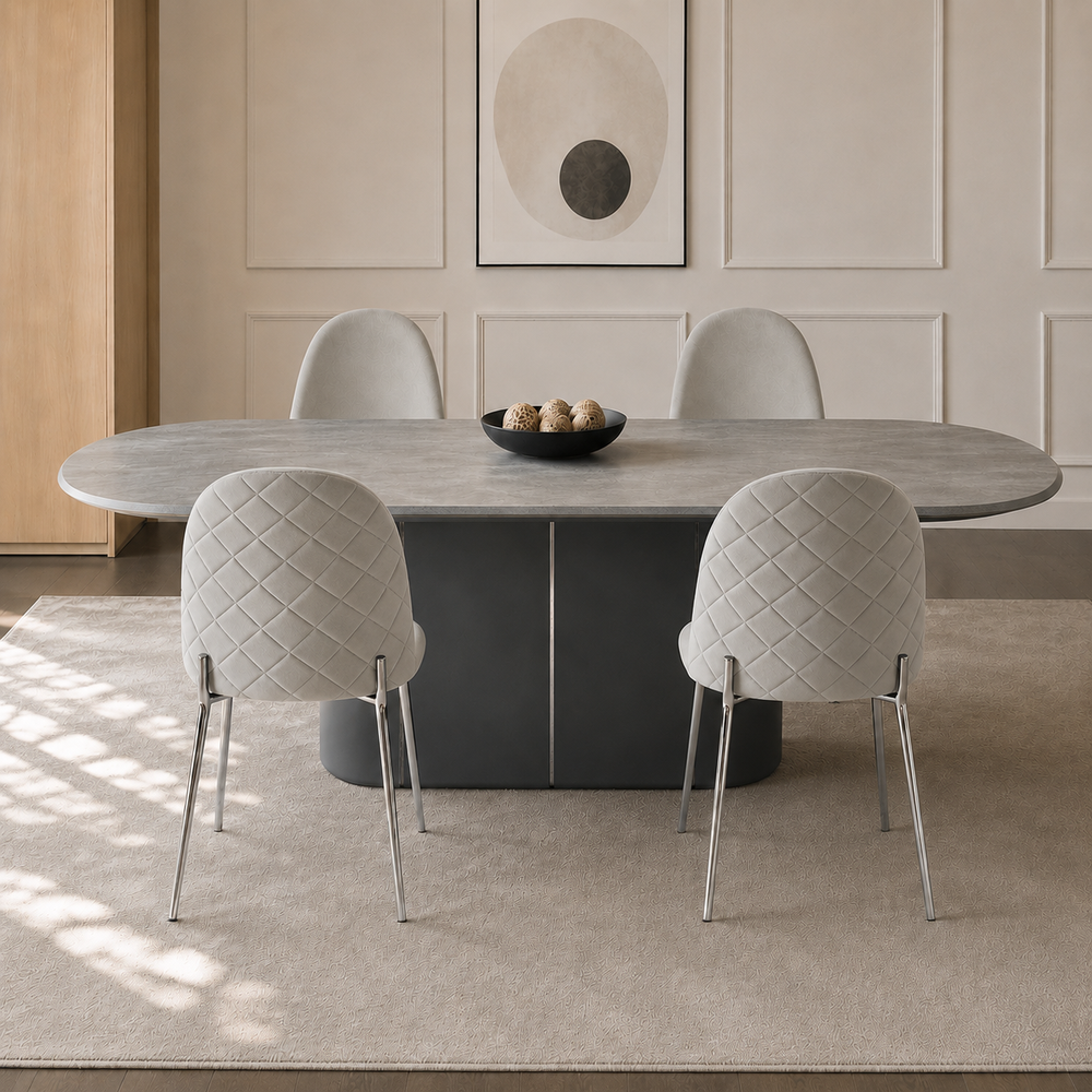 Cuatro sillas Catania en pana gris claro dispuestas alrededor de una mesa de comedor ovalada.