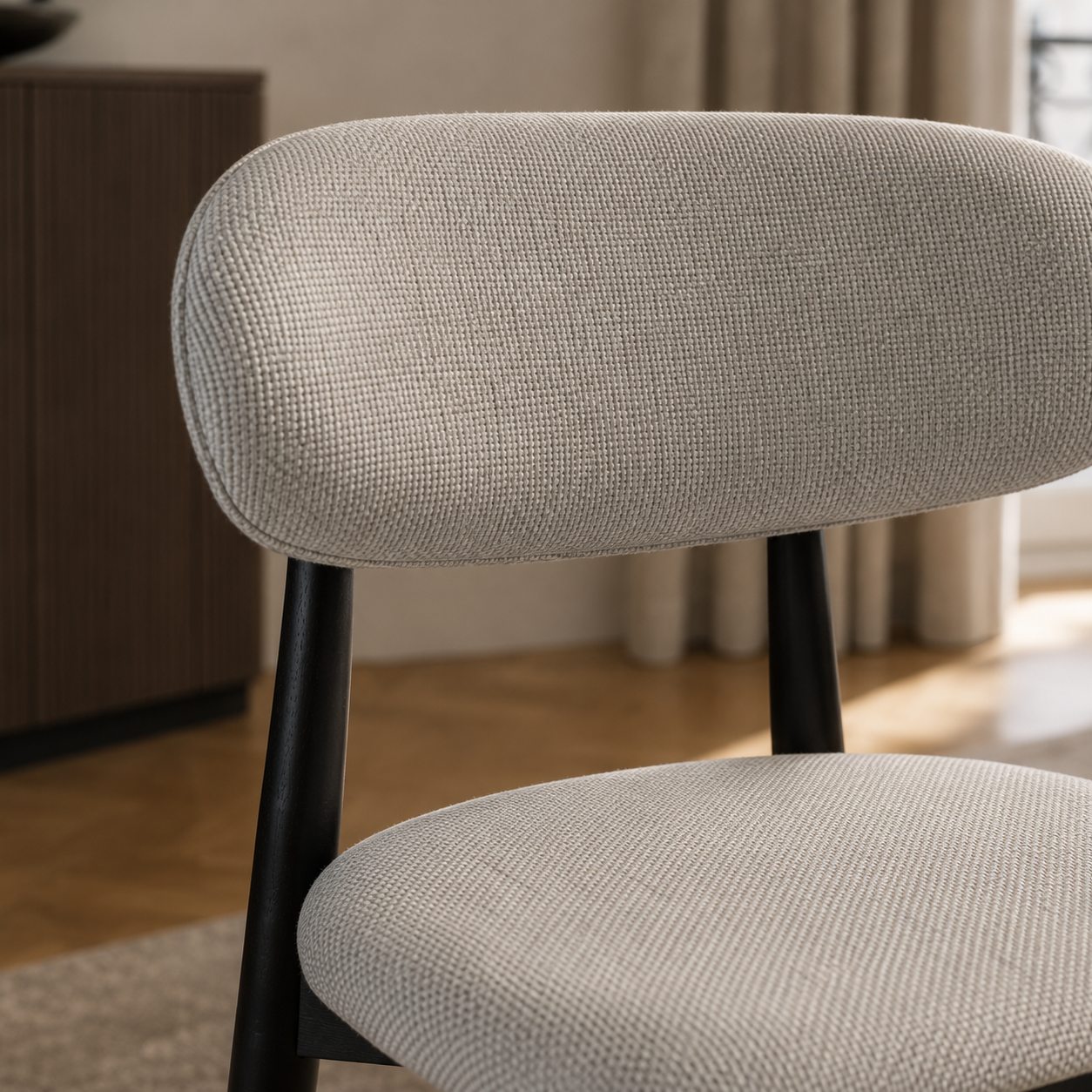 Primer plano de la textura del tapizado en chenille gris claro sobre el respaldo y asiento de la silla Zuno Deluxe.