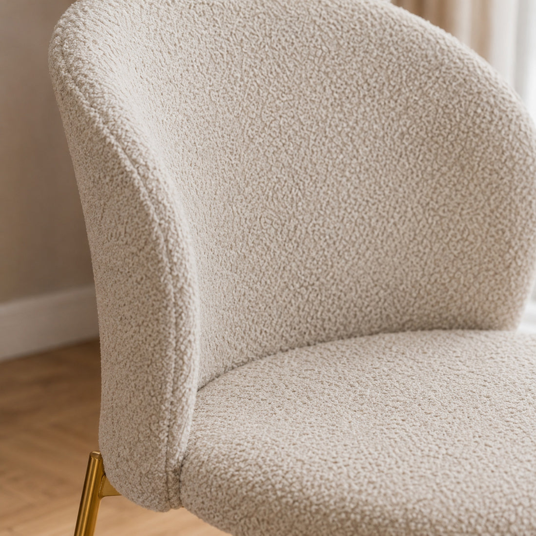 Primer plano del tejido bouclé color beige en el respaldo envolvente de la silla Elira.