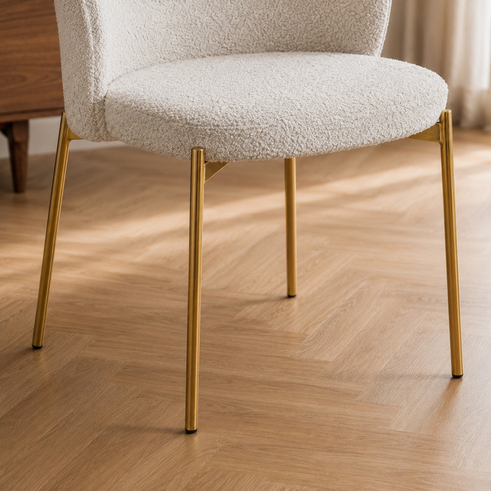 Detalle del asiento de la silla Elira y la unión con sus patas metálicas de acabado dorado.