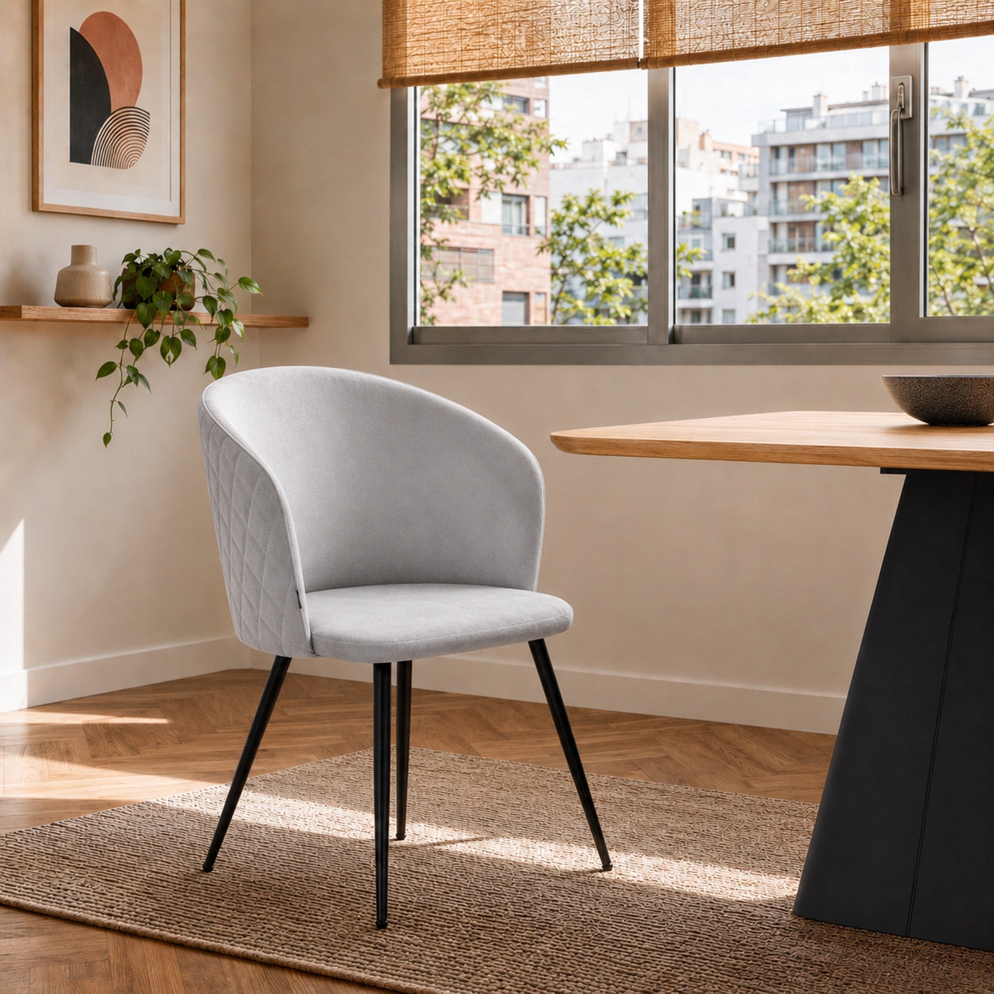 Silla Jade con tapizado gris claro y base negra, ubicada junto a una mesa de comedor en un espacio moderno.