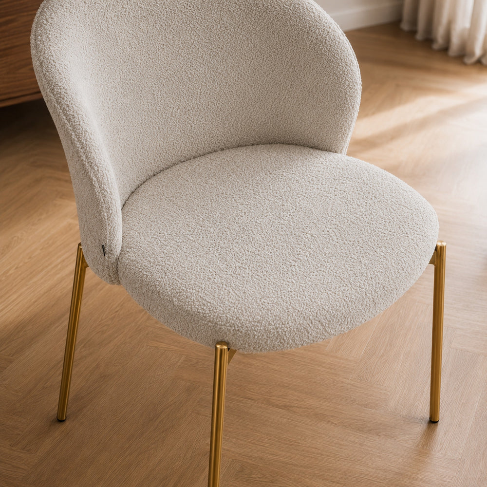 Perspectiva superior del asiento circular y respaldo curvo de la silla Elira en bouclé beige.