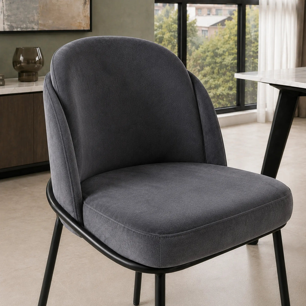 Detalle del tapizado gris oscuro y la costura del asiento de la silla Katia con base metálica negra.