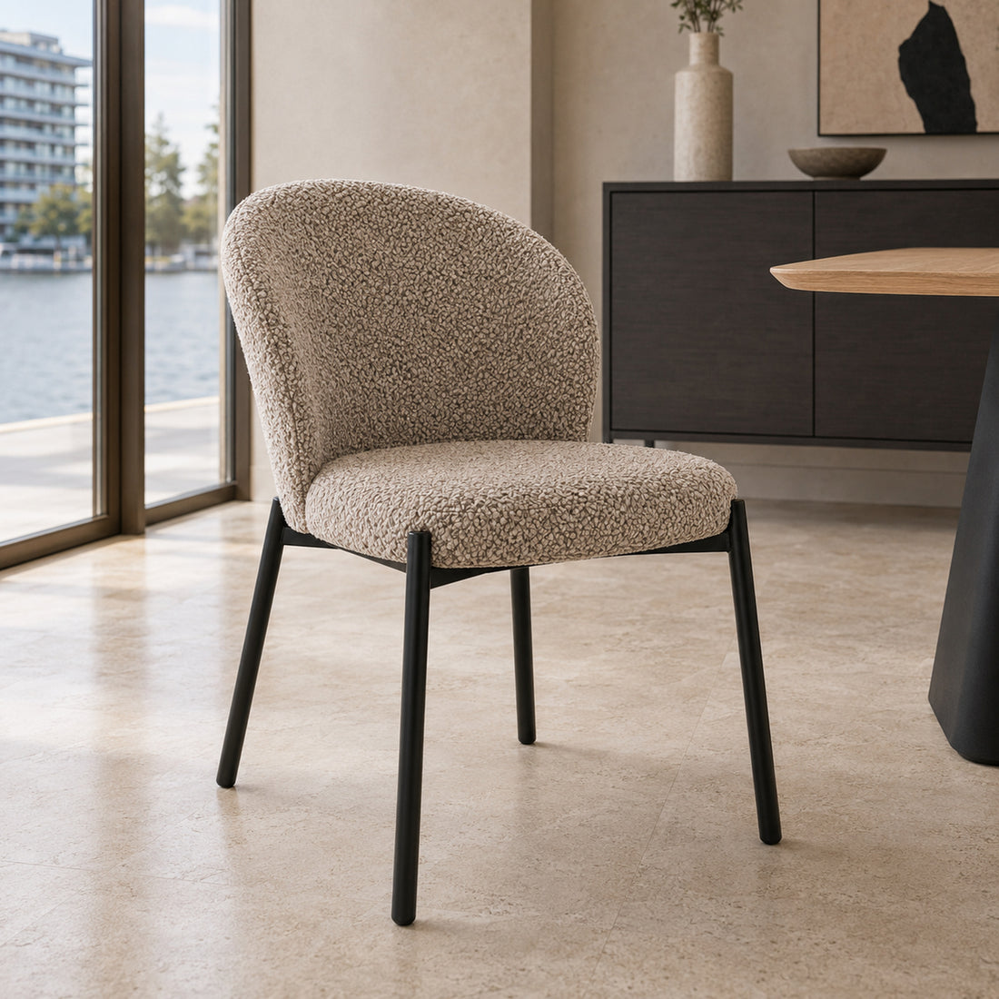 Silla Elira tapizada en bouclé color taupe con base metálica negra en vista frontal de tres cuartos.