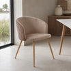 Silla Jade en pana color taupe con base de madera natural y diseño envolvente de líneas curvas.