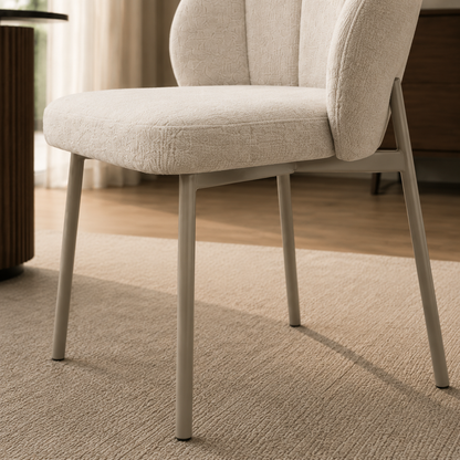 Primer plano de la base metálica en tono capuccino y el asiento envolvente de la silla Dublin en chenille gris.