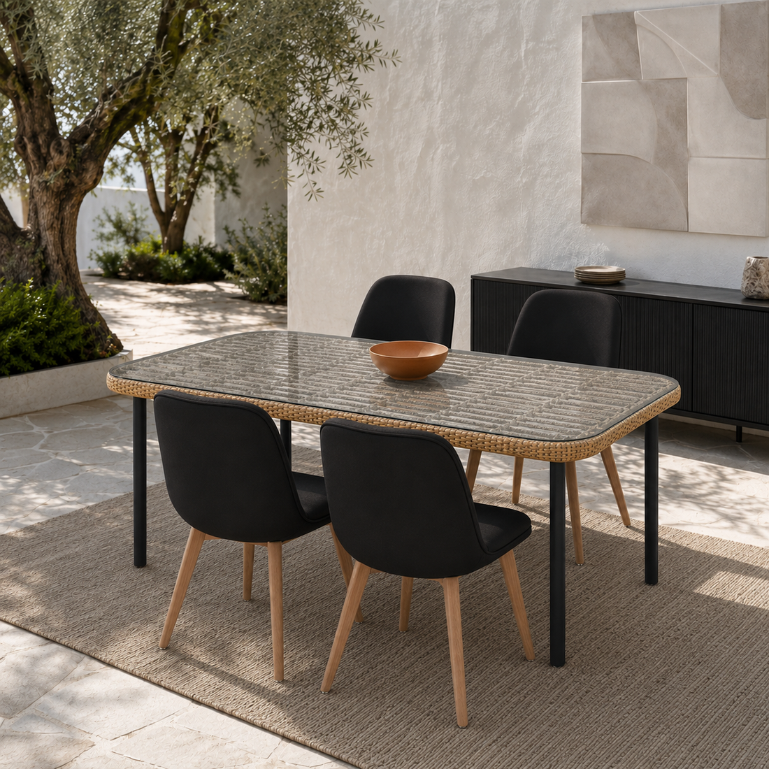 Mesa de exterior Bruce con superficie de vidrio, rodeada de cuatro sillas negras en una terraza.
