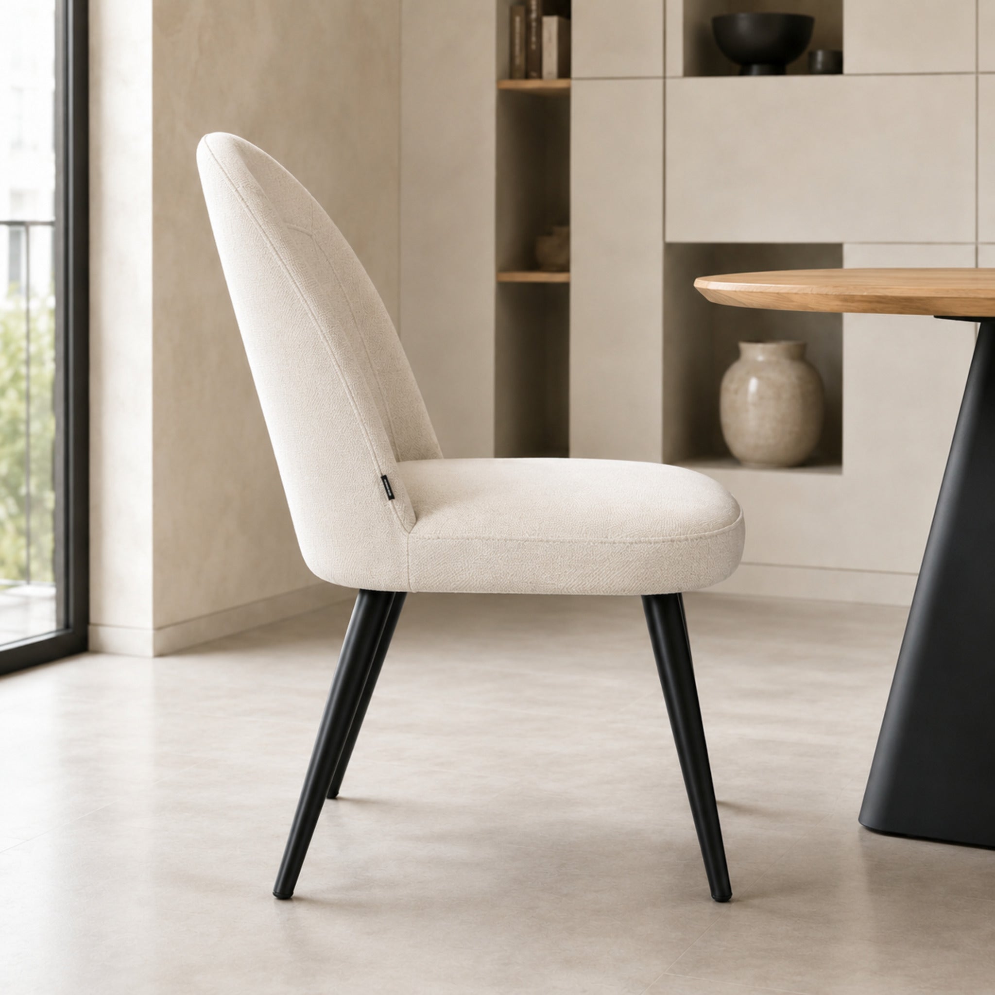 Perfil lateral de la silla Lara beige con base negra que muestra la inclinación del respaldo y estructura.