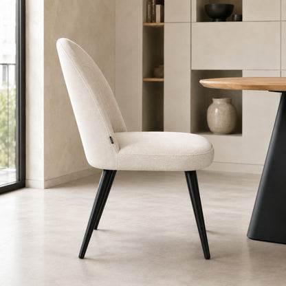 Perfil lateral de la silla Lara beige con base negra que muestra la inclinación del respaldo y estructura.