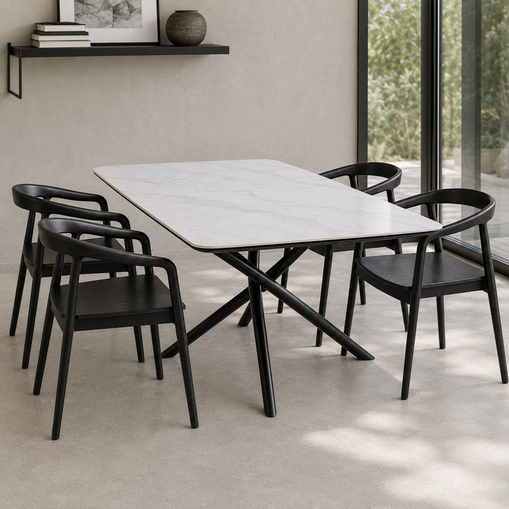 Cuatro sillas Praga Circle negras de madera maciza dispuestas alrededor de una mesa de comedor blanca.