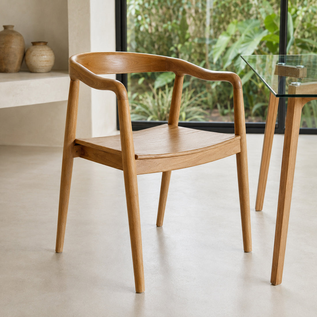 Silla Praga Circle Teka en madera maciza laqueada, vista frontal tres cuartos junto a una mesa de vidrio.