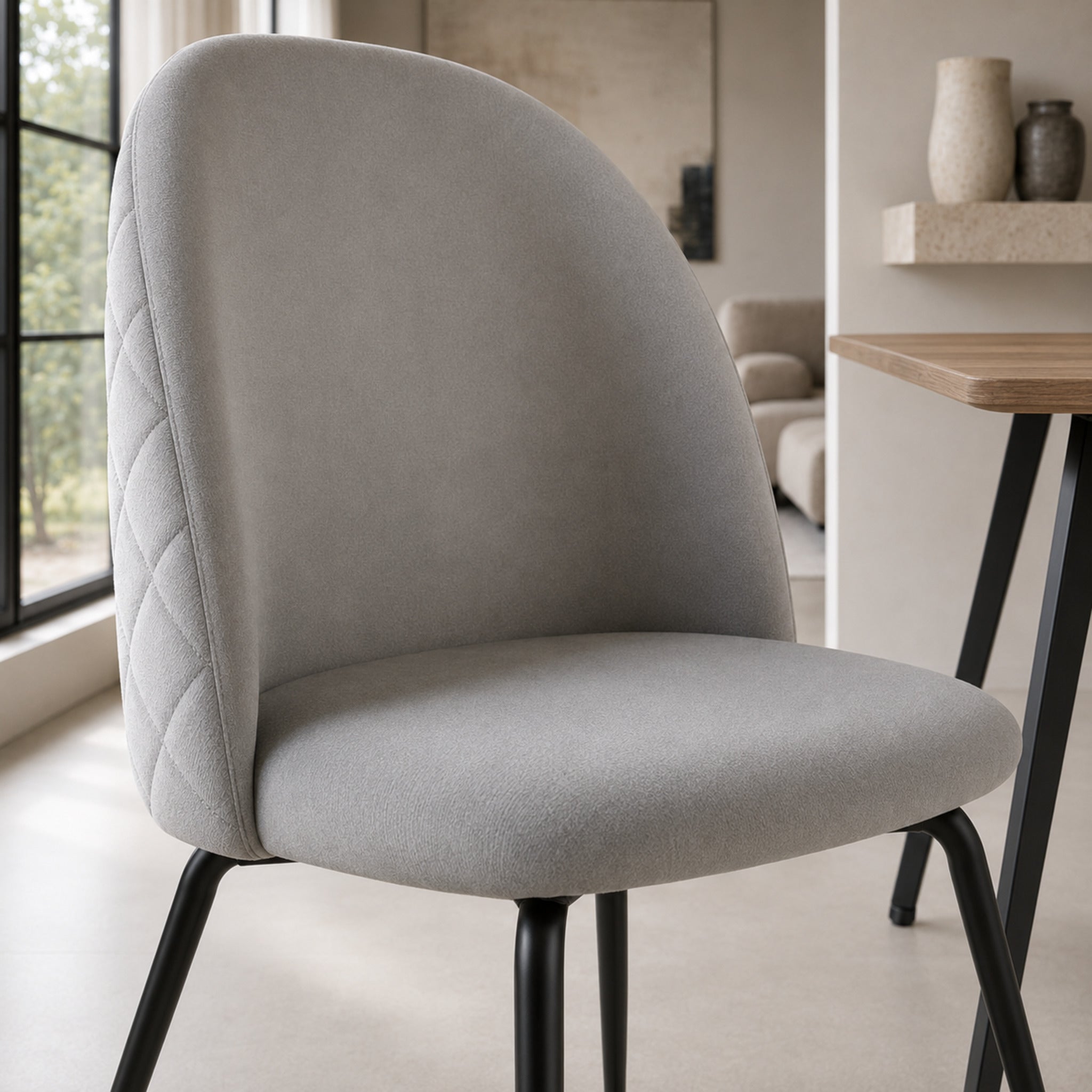 Primer plano del asiento acolchonado y la base del respaldo de la silla Venecia en pana color gris claro.