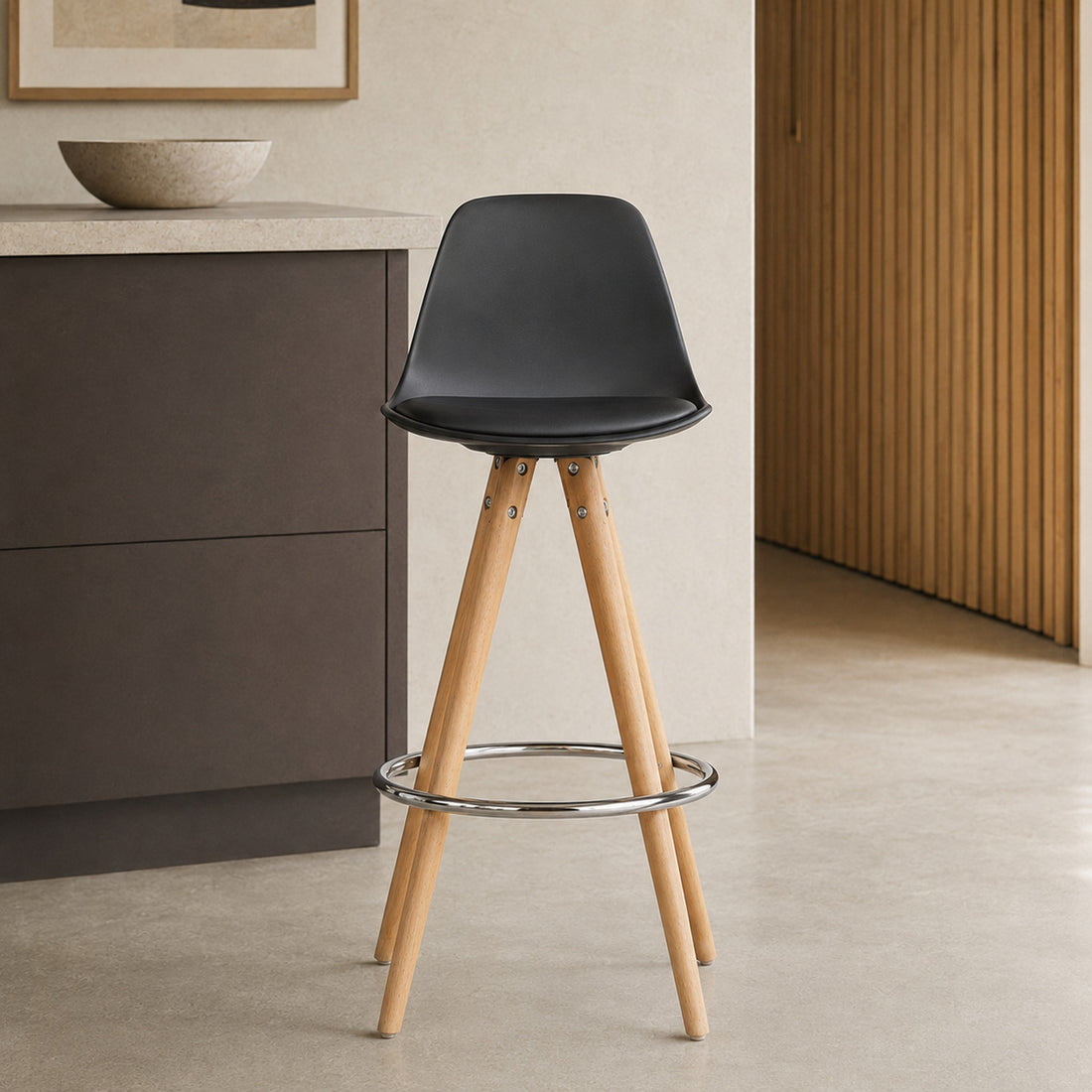 Banqueta Elba negra de frente con estructura de madera clara y aro apoyapiés cromado circular.