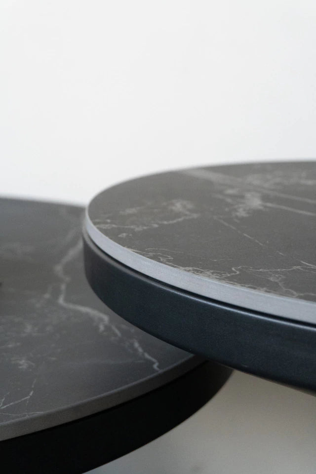 Primer plano del borde de la tapa de Neolith y la estructura de metal negro mate de la mesa auxiliar Minolta.