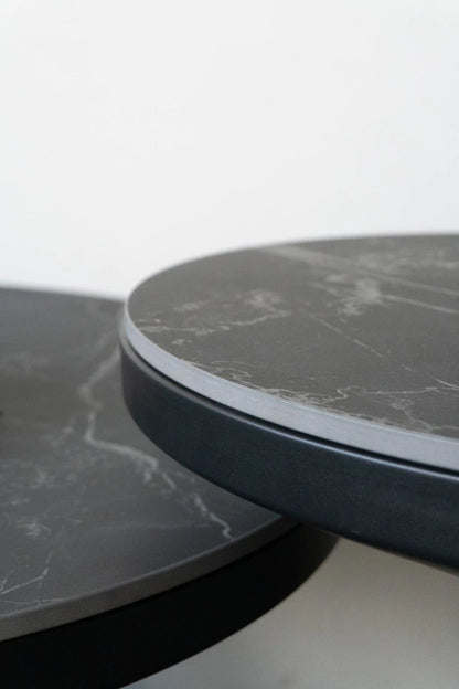 Primer plano del borde de la tapa de Neolith y la estructura de metal negro mate de la mesa auxiliar Minolta.