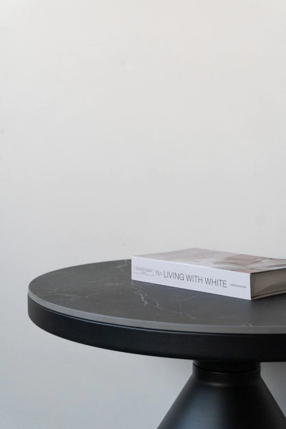 Mesa auxiliar Minolta con tapa de Neolith y base cónica metálica en un espacio de diseño contemporáneo.