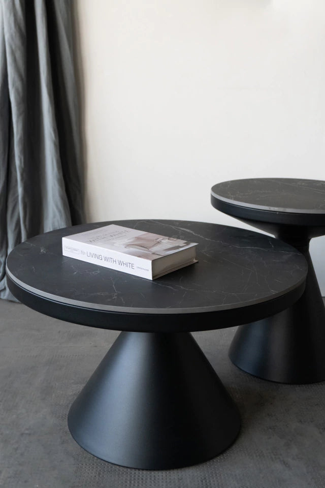 Detalle de la mesa auxiliar Minolta baja con tapa de Neolith oscura y libro decorativo en un ambiente moderno.