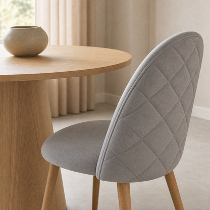 Detalle del respaldo matelasseado de la Silla Livia gris claro de pana con Mesa Ewan madera natural de fondo