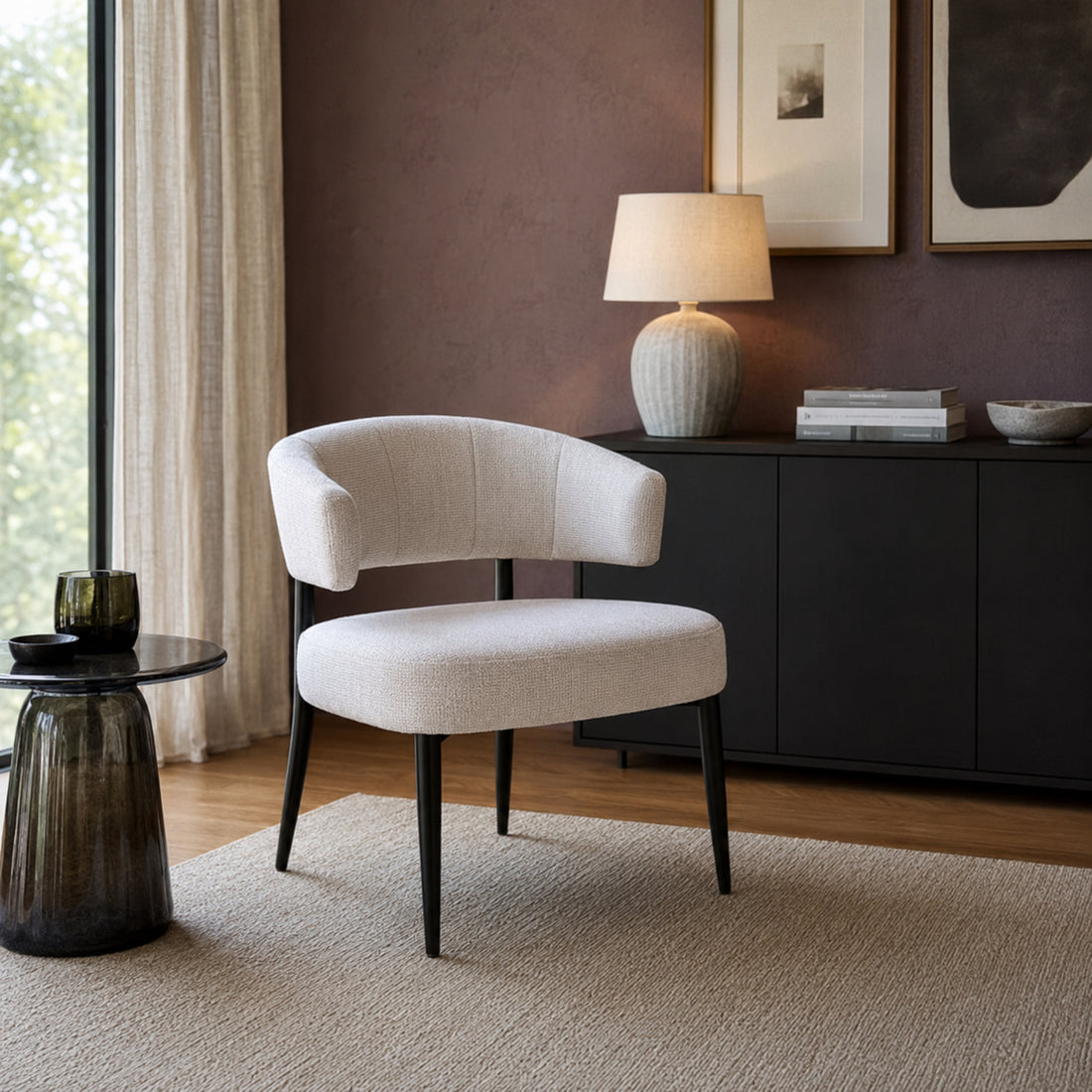 Sillón Bondie tapizado en chenille beige con base de hierro negra, vista lateral en ambiente de living.