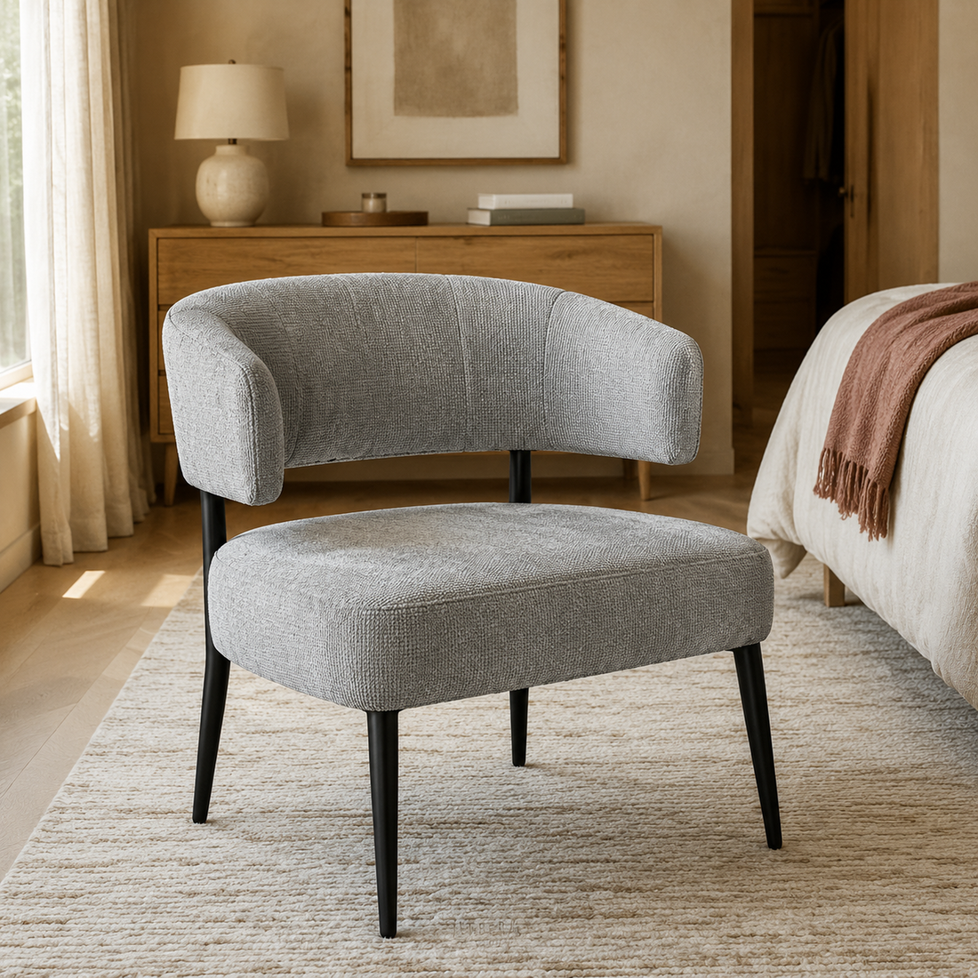 Sillón Bondie tapizado en chenille gris con base negra de hierro, vista en perspectiva en un ambiente moderno.