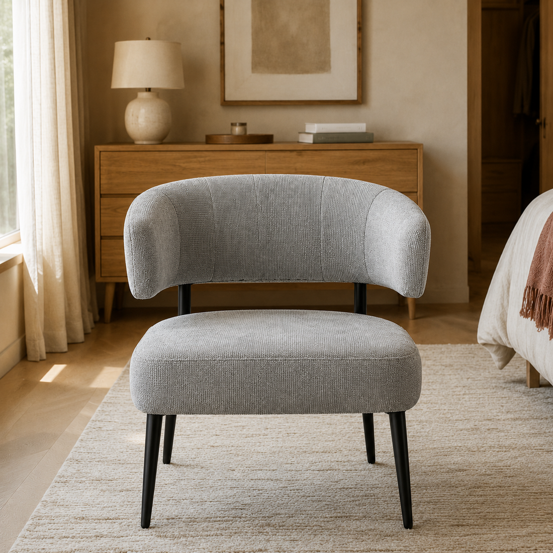Sillón Bondie de frente, destacando el tapizado en chenille gris y la estructura de patas negras.