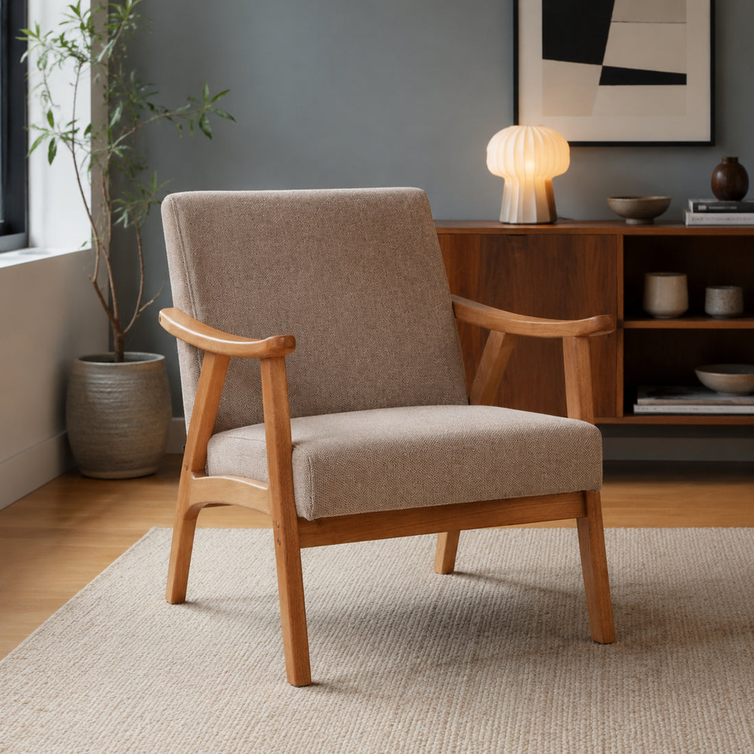 Sillón Laurel en chenille taupe con base de madera natural, vista de tres cuartos en un living con alfombra neutra.