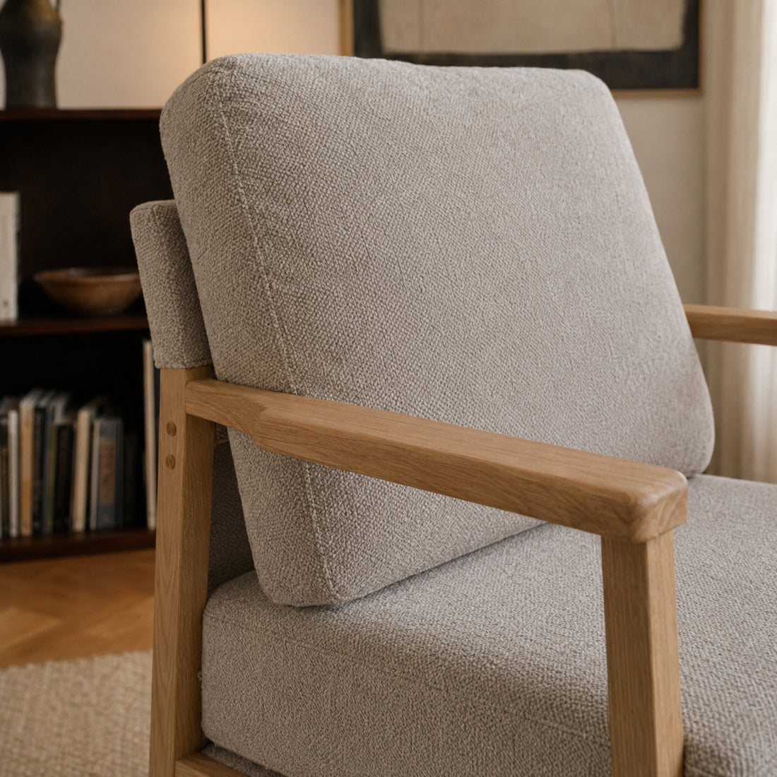 Primer plano del tapizado en chenille taupe y el apoyabrazos de madera natural del sillón Niko.