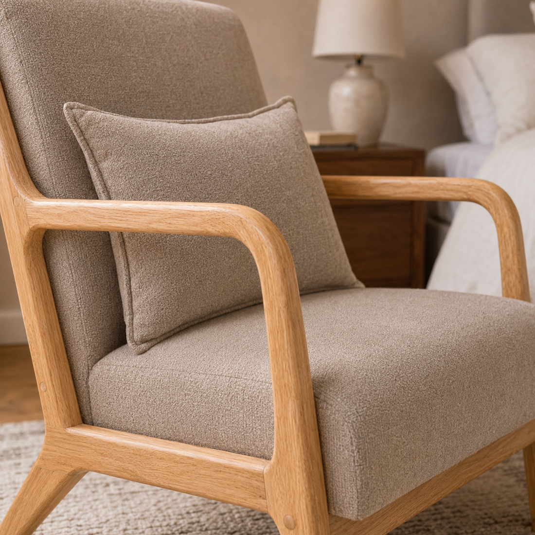 Detalle del apoyabrazos de madera natural y la textura del tapizado en chenille taupe del sillón Olia.